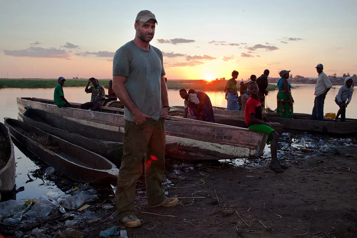 Ed Stafford riverbank portrait with local boats, Zimbabwe