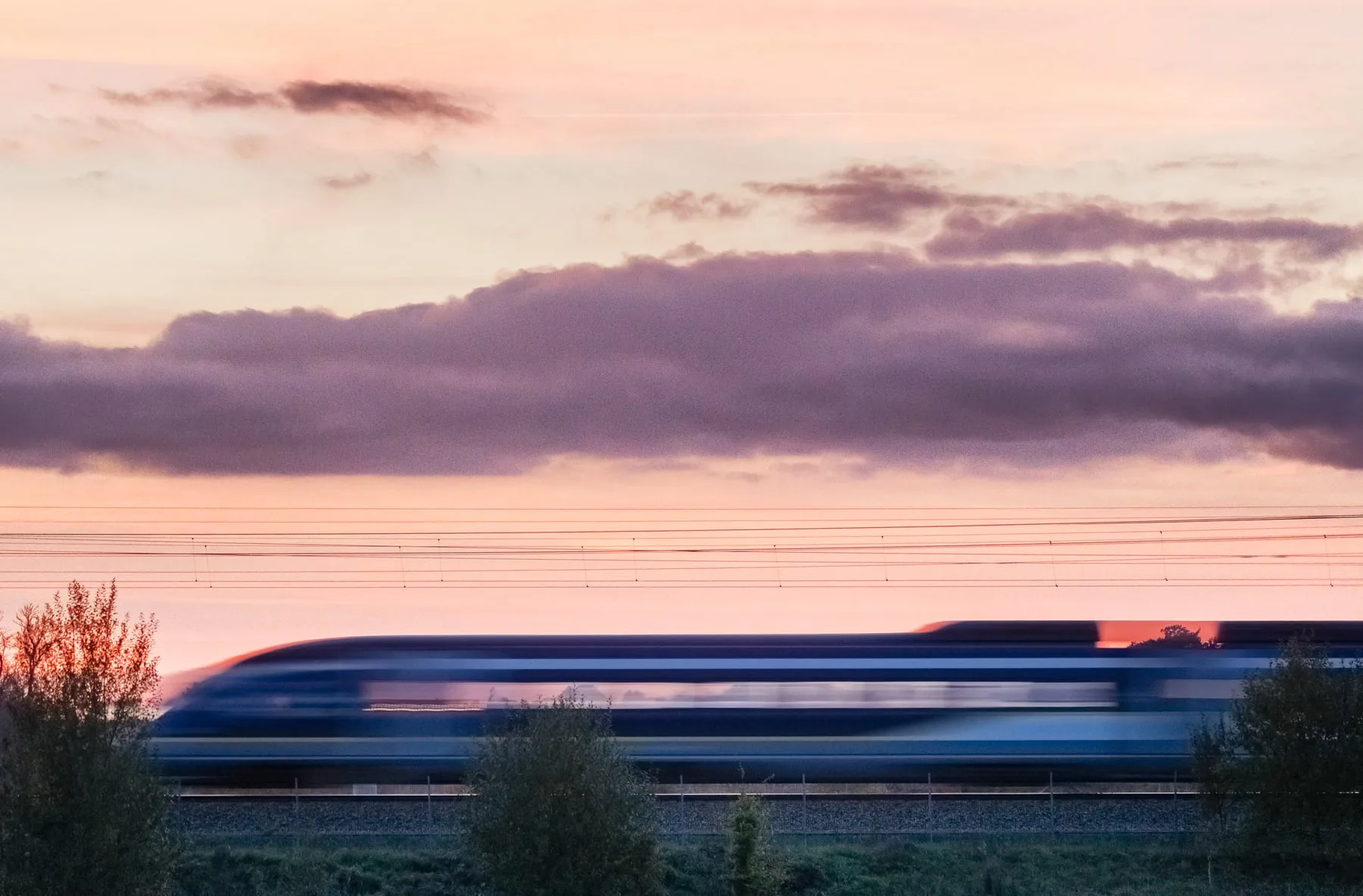 Eurostar train passing green hills with grazing horses, Kentish countryside