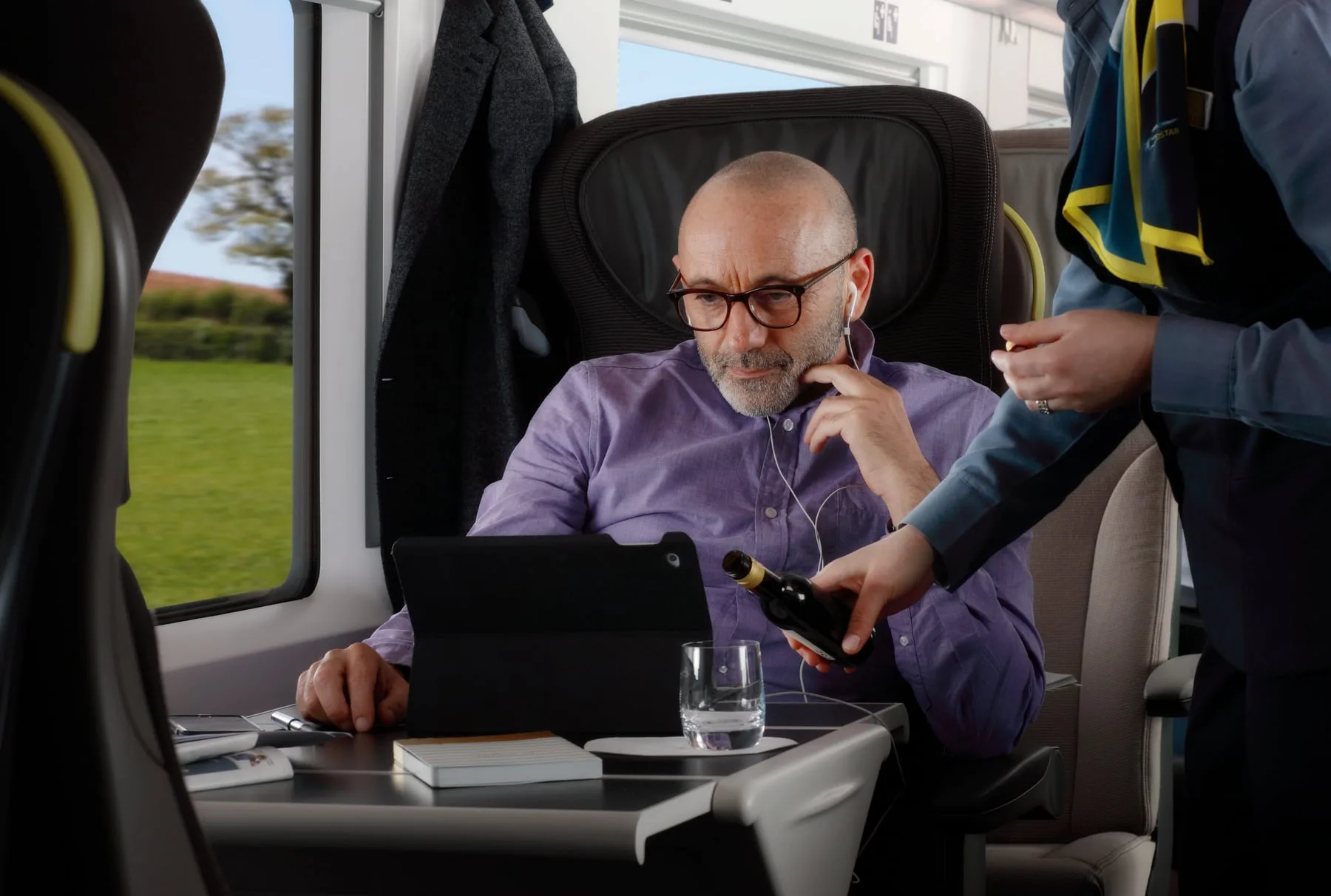 Onboard wine service on Eurostar for a passenger watching a tablet