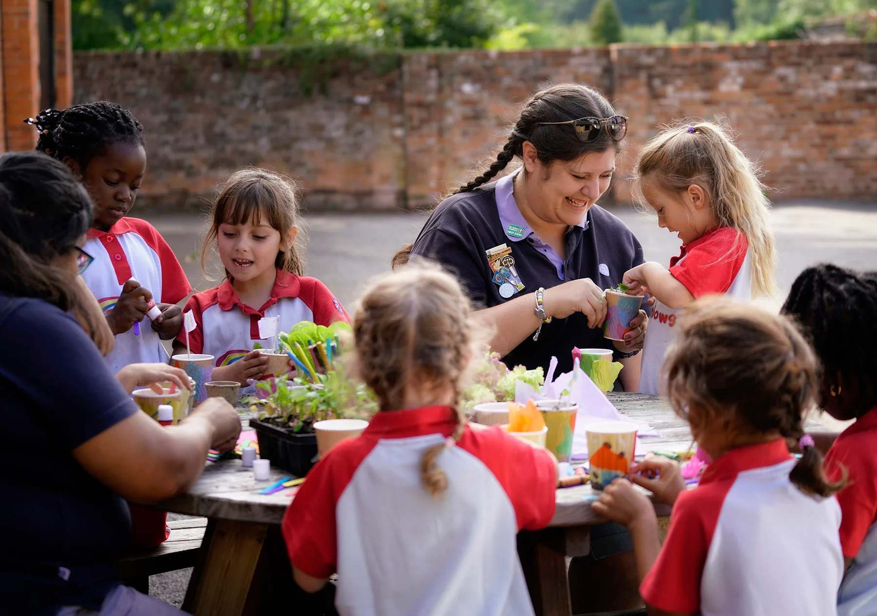 A Girlguiding leader helping girls pot seedlings at a craft table, Inspire Girls
