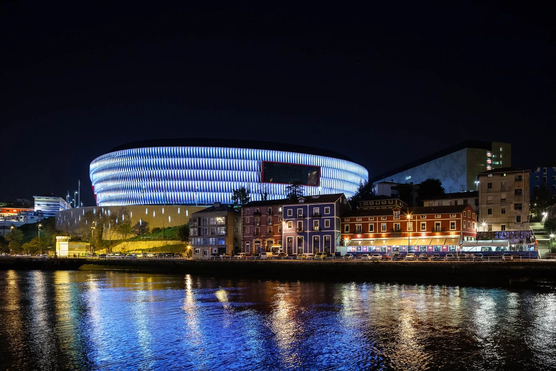 San Mamés Stadium glowing blue over the Bilbao waterfront at night — OSRAM