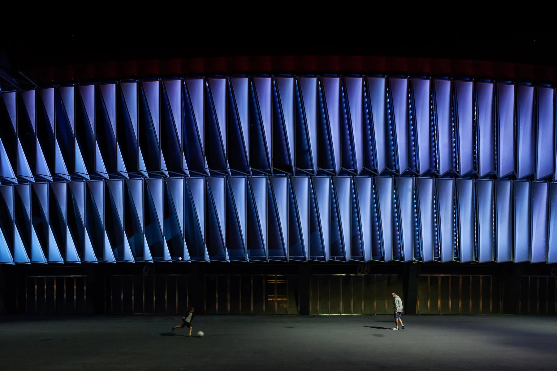 Children playing football beneath the illuminated San Mamés façade, Bilbao — OSRAM
