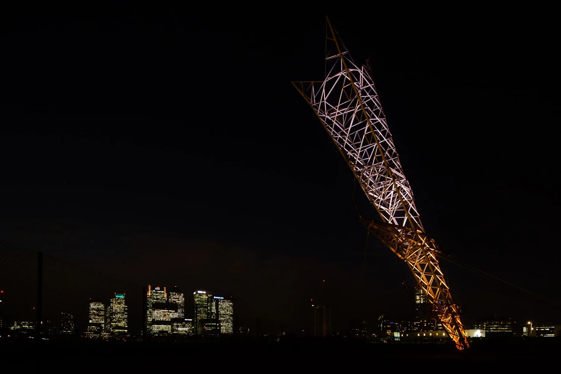 Chinneck's leaning-pylon sculpture lit at night on Greenwich Peninsula, London — OSRAM