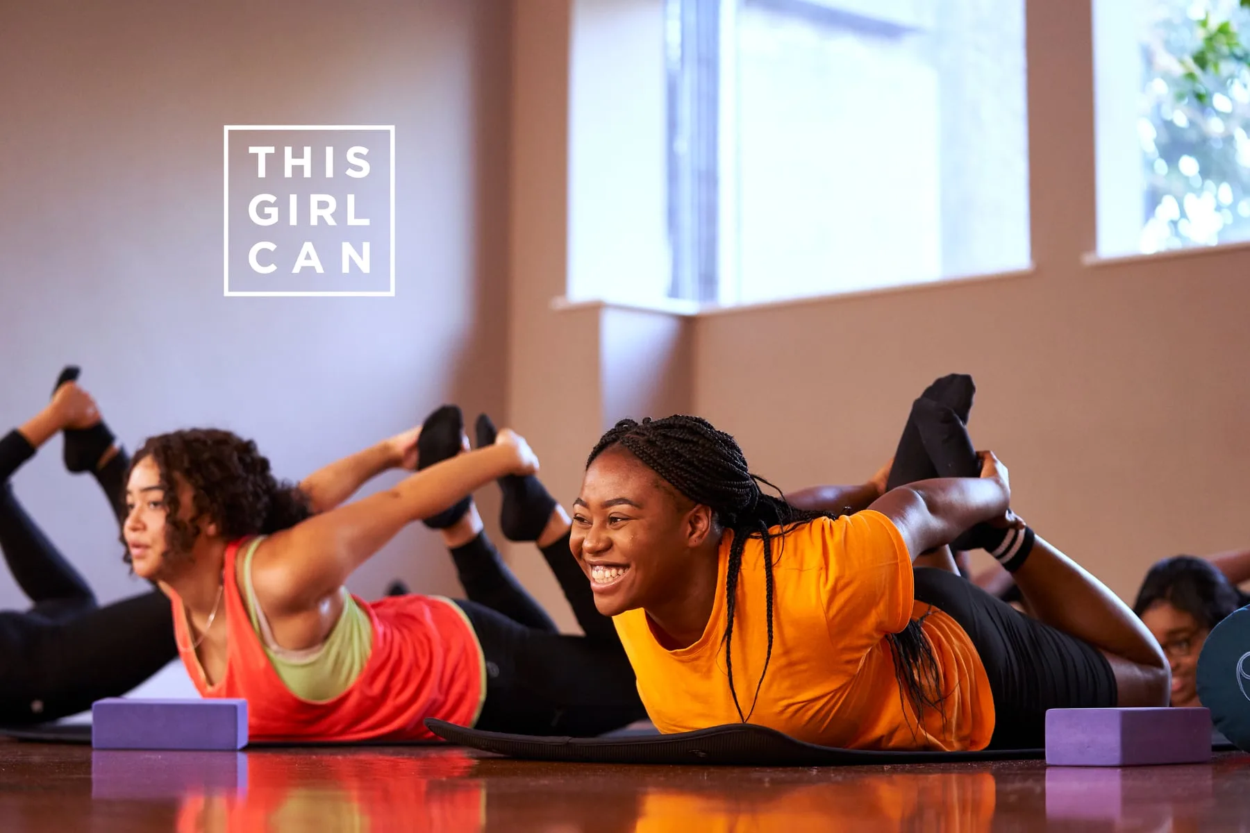Two women in a pilates stretch on studio mats, This Girl Can