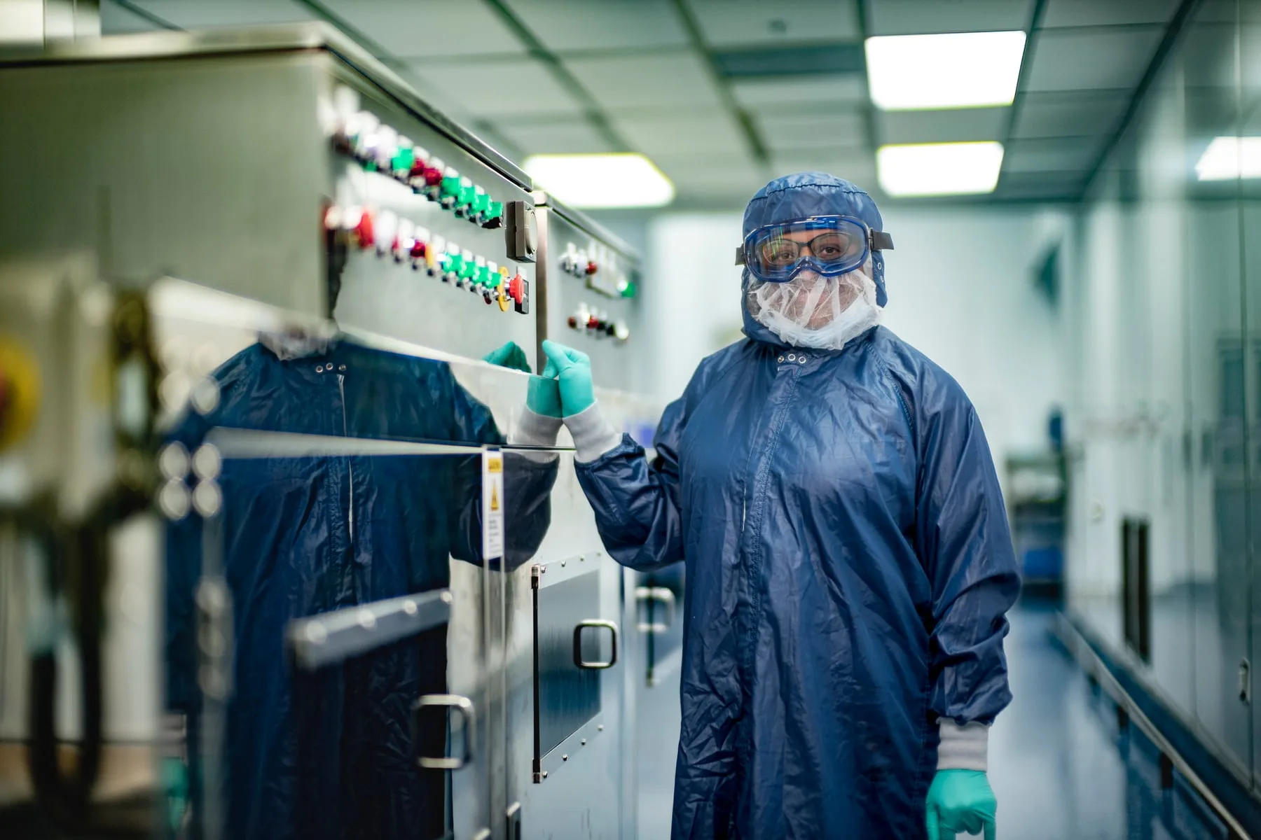 A West Pharmaceuticals cleanroom operator in full coveralls beside production equipment in North Carolina